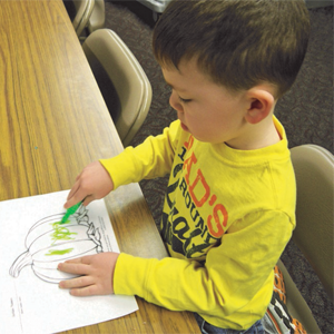 child coloring a pumpkin